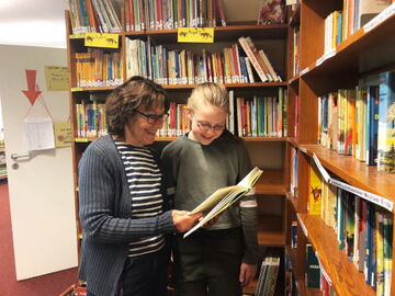 Ehrenamt in der Schulbibliothek: Gesina Kegel schaut gemeinsam mit Schülerin in Buch Gesina Kegel schaut gemeinsam mit Schülerin in Buch - Ehrenamt in der Schulbibliothek